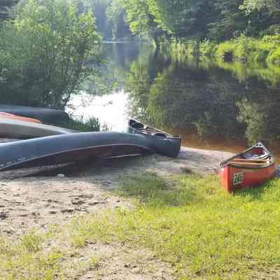 The Dennys River at Robinson's Cottages: Canoes and watercraft line the beach as the Dennys River rounds the bend above Robinson's Cottages in Edmunds, Maine.  Registered Maine guides lead expeditions for fishermen, hunters and other who wish to explore the Maine woods.