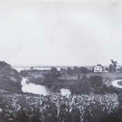 Dennys River in Meddybemps, Maine, c. 1930: Detail of a panoramic view of Meddybemps village c. 1930.  Note the field to the left which was later uncovered as an ancient Passamaquoddy Village site.