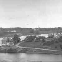          Houses on Foster Lane above T.W. Allan's Shipyard, c. 1885; Three houses are visible on Foster Lane on the far side of the Dennys River, beyond T.W. Allan's wharf and Hobart house in the foreground.  T.W. Allan and Son also owned  the shipyard where the schooner is moored in the distance, and the house above the blacksmith shop near the shore.
   