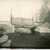          Dam at the head of the Dennys River on Meddybemps Lake, c. 1960; Water from Meddybemps Lake flows under the raised gate of the dam at the head of the Dennys River in Meddybemps, Maine.
   