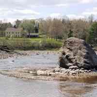          Rock Peter stands sentinel-like on the Edmund side of the Dennys River in eastern Maine, with the remains of T.W. Allan's wharf visible to the left, and the Lincoln House in the distance.  As part of the bedrock, Rock Peter served as the origin or starting point for all of the early surveys of the local area.
   