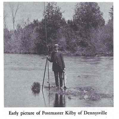 Howard Kilby, Dennysville Postmaster displaying a freshly caught salmon caught on the Dennys River in the late nineteenth century.: Note the length of his fly rod, waders and the gaff hook in his hand, as well as the size of his catch.