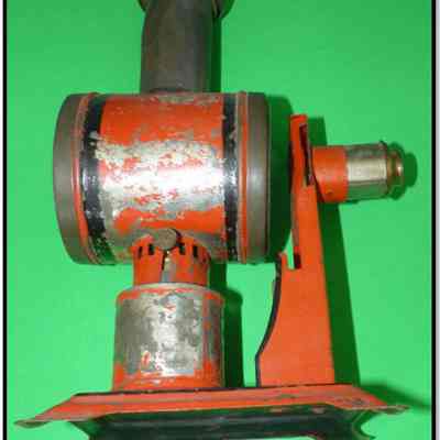 This is an image of a red and silver vintage Magic Lantern projector against a green background.